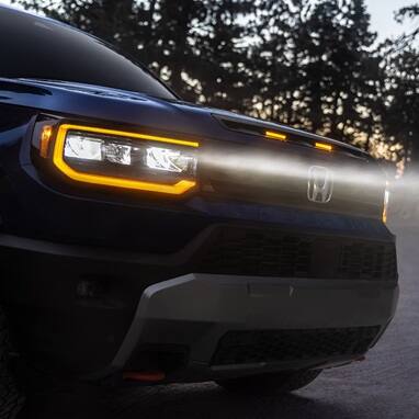 2027 Honda Passport TrailSport Elite in Smoke Blue Pearl front outdoors at dusk with glowing headlights (Mid-Size SUV).