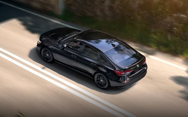 2027 Honda Civic Sedan Sport in Crystal Black Pearl high-angle rear three-quarter view driving on a road (Compact Sedan)